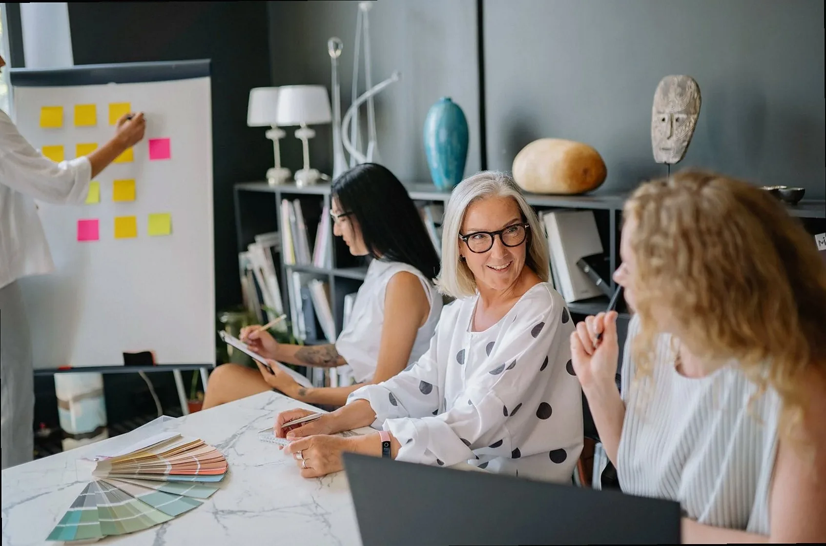 Diverse women collaborating in a stylish office during a creative brainstorming session with post-it notes.